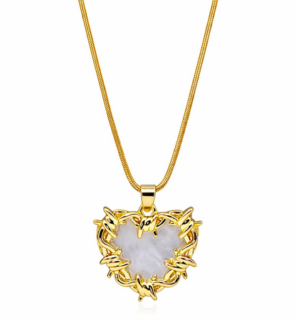 Gold heart-shaped pendant necklace with a white stone on a white background